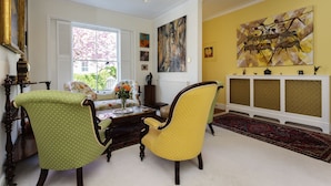 A living room with two armchairs, a coffee table, and a large painting on the wall. - The Gallery of Colour, by Veeve (London)