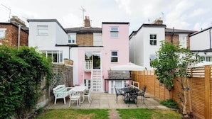 A residential backyard with a patio, a barbecue area, and a white fence. - The Gallery of Colour, by Veeve (London)
