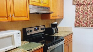 A kitchen with wooden cabinets, a microwave, a stove, and a coffee maker. - Near Siesta Key. Lg Patio. 2 King beds, Wi-Fi, Updated Sarasota Condo. 1st floor (Sarasota)
