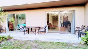 An outdoor patio with a table and chairs, a sliding glass door leading to an interior space, and a small garden area. - Near Siesta Key. Lg Patio. 2 King beds, Wi-Fi, Updated Sarasota Condo. 1st floor (Sarasota)