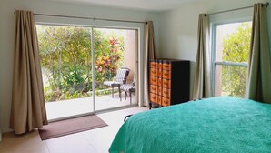 A bedroom with a bed, a dresser, and a sliding glass door leading to an outdoor area with a chair and plants. - Near Siesta Key. Lg Patio. 2 King beds, Wi-Fi, Updated Sarasota Condo. 1st floor (Sarasota)