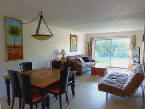 Un espace repas comprenant une table et des chaises, un canapé et une grande fenêtre donnant sur un paysage verdoyant.