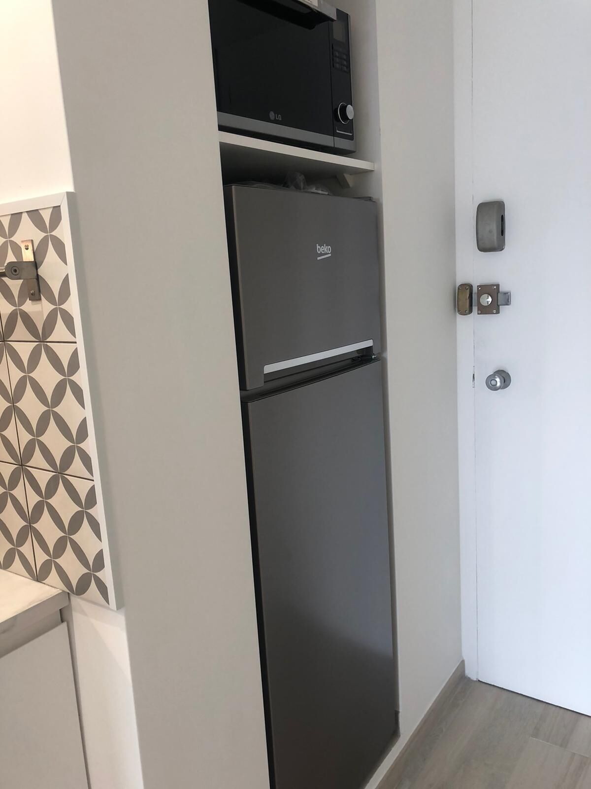Een keuken met een zwarte koelkast, een magnetron en een decoratieve achterwand.