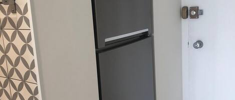 Una cocina con un refrigerador negro, un microondas y un protector contra salpicaduras con diseño.