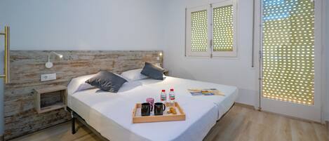 A modern bedroom with a wooden headboard, a bedside table with a lamp, a bed with pillows, a tray with breakfast items, and a window with a patterned blind.