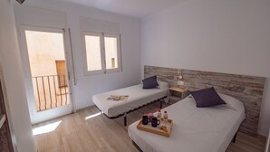 Un dormitorio con dos camas, cabeceros de madera, mesitas de noche con lámparas y una bandeja con bebidas y aperitivos.