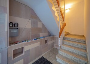 A modern staircase with a wooden handrail and a check-out machine on the wall.