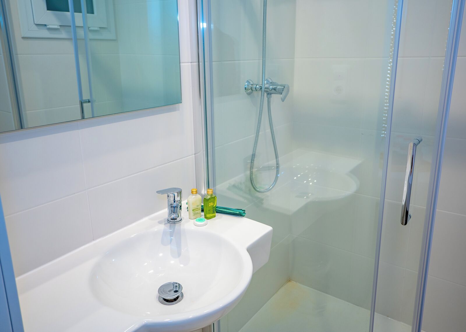A bathroom with a white sink, a glass shower enclosure, and a mirror above the sink.