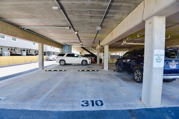 Eine Tiefgarage mit Betonstützen, markierten Parkplätzen und einem Schild, das zugewiesene Stellplätze anzeigt.