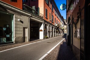 Eine schmale Straße, gesäumt von Häusern, darunter eine Apotheke und ein Geschäft mit einer Schaufensterpuppe.