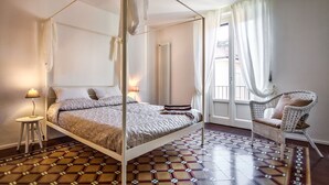 A four-poster bed with a white canopy, a wicker chair, and a patterned rug. - REGINA  24 APARTAMENT (Cernobbio)