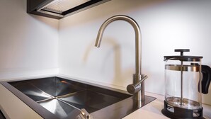 A modern kitchen with a sleek stainless steel sink, a single faucet, and a coffee press on the counter. - REGINA  24 APARTAMENT (Cernobbio)