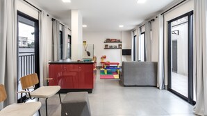 A modern living room with a red kitchen area, a gray sofa, and a colorful play area. - Flat completo com garagem, 2 camas de casal, perto do Centro e Jd Bot, PUC (Rebouças)