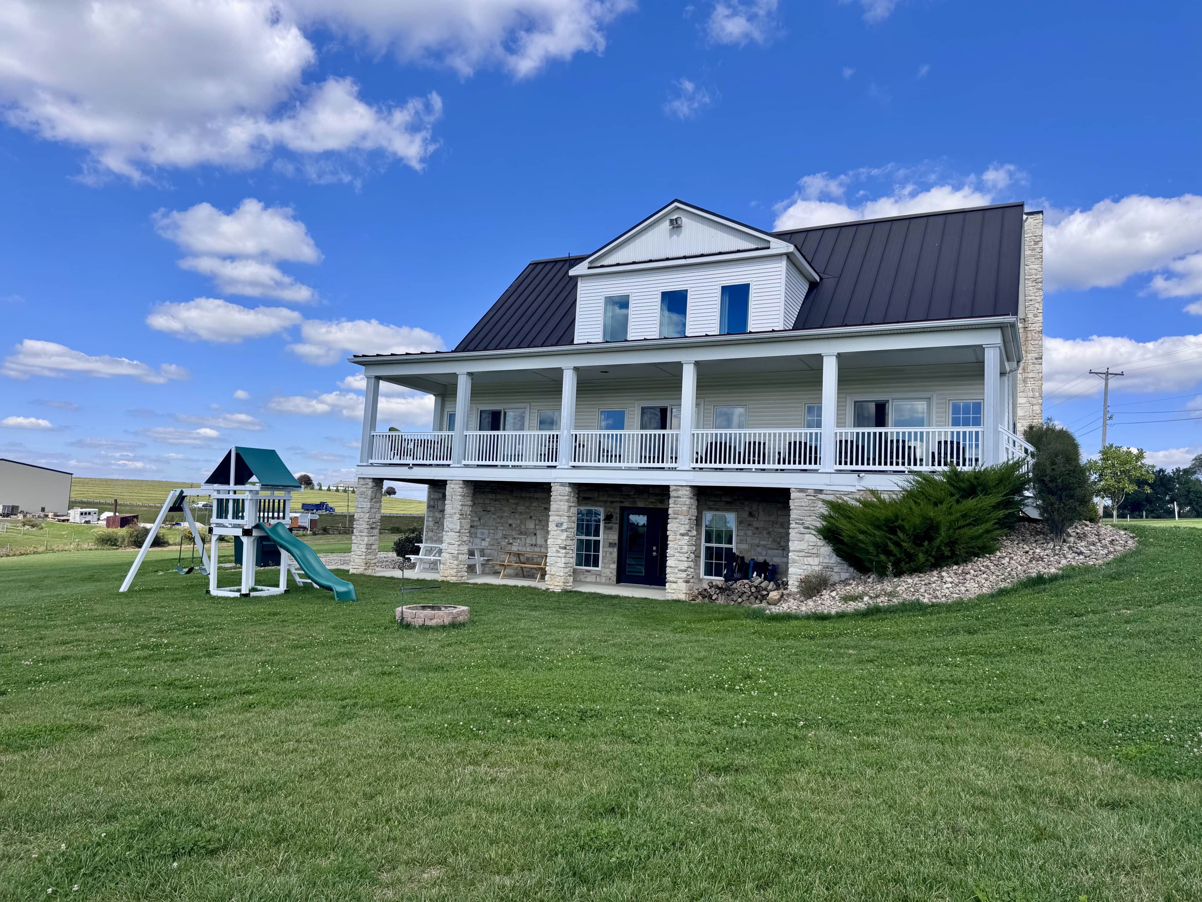A two-story house with a porch and a swing set in the yard.