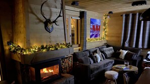 A cozy living room with a fireplace, a couch, and a dog. - Chalet Individual warm  (Megève)