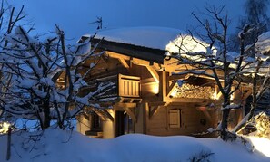 Una baita di legno con un balcone, circondata da alberi coperti di neve.