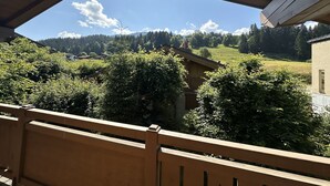 A wooden balcony with a view of a green landscape and distant mountains. - Chalet Individual warm  (Megève)