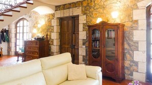 Un salon avec un canapé en cuir blanc, un meuble en bois et un mur en pierre.
