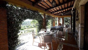 Une terrasse couverte avec des sièges d’extérieur, des murs en briques et une vue sur le paysage environnant.