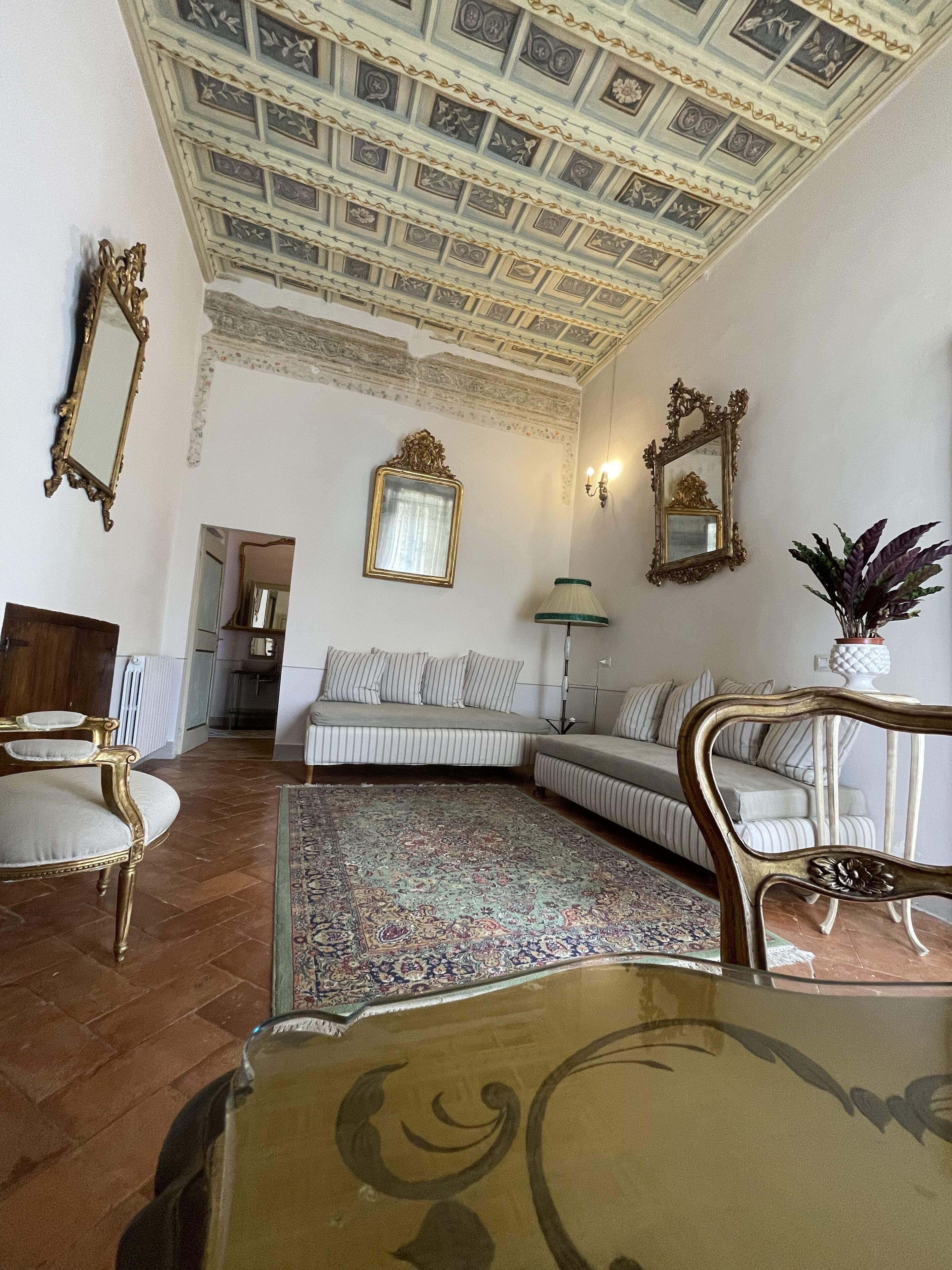 A room with a patterned carpet, a sofa, a chair, and a table.