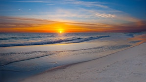 Una spiaggia con il sole al tramonto sull'oceano.