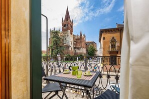 Un balcón con una mesa para dos, con vistas a una iglesia histórica de gran torre.