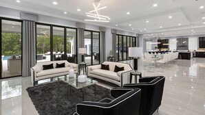 A spacious living area with a sofa, armchairs, and a glass coffee table. - White House at Reunion | 10BR Luxe Stay w/ Bowling Alley, Arcade, Private Pool, and Gym Near Disney (Kissimmee)