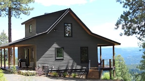 Eine zweistöckige Holzhütte mit Veranda, überdachter Terrasse und Bergblick.