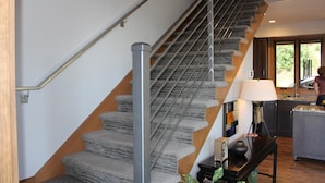 Eine Treppe mit Metallgeländer und Teppichstufen, die zu einer Zwischenebene führen.