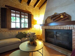 A cozy living room with a brick fireplace, a sofa, and a coffee table. - Rural house capacity from 2 to 16 people, house for 12 and suitable for 2/4 pax (San Carlos del Valle)