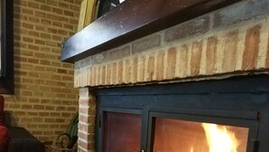 A brick fireplace with a glass door, a potted plant on top, and a wicker basket beside it. - Rural house capacity from 2 to 16 people, house for 12 and suitable for 2/4 pax (San Carlos del Valle)