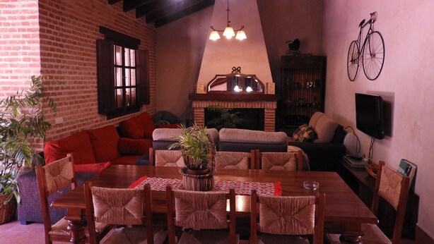 A cozy living room with a brick wall, a fireplace, and a dining area with a wooden table and chairs.