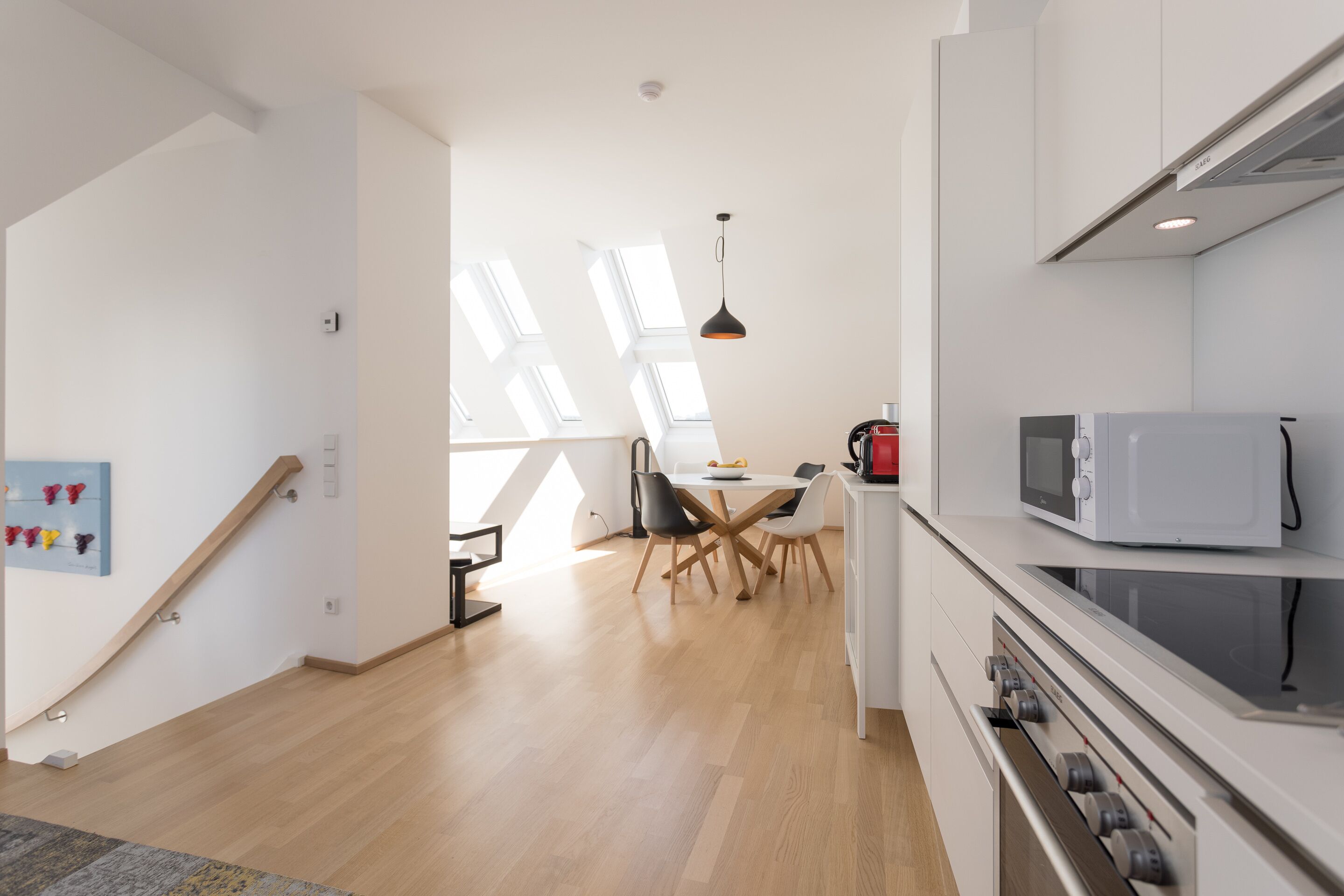 A modern kitchen with a microwave, stove, and dining area with a table and chairs.