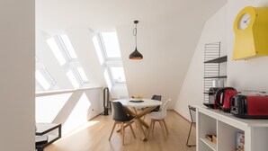 Een moderne keuken met een wit aanrecht, een rode toaster en een gele klok aan de muur.