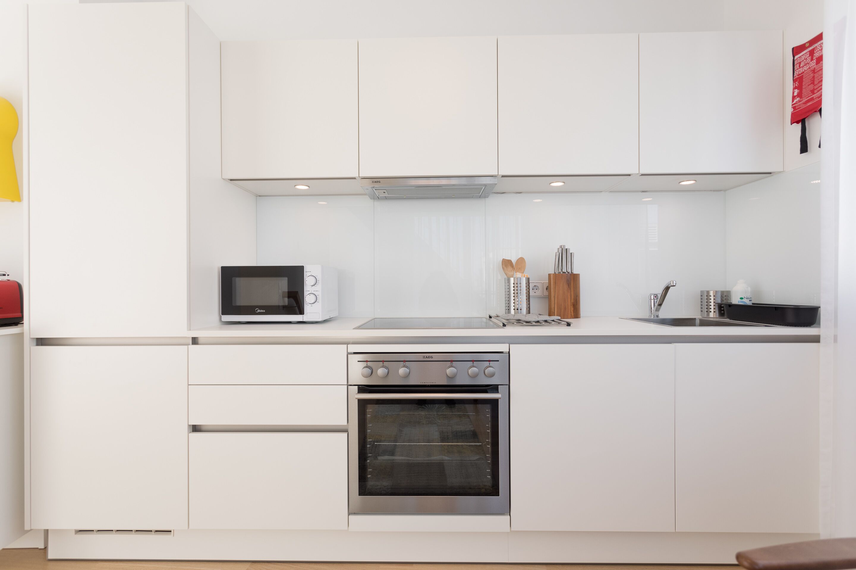 A modern kitchen with white cabinetry, a built-in microwave, a stove, and a sink.