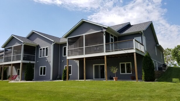 A two-story house with a balcony, a covered porch, and a well-maintained lawn.