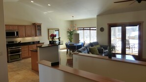 A spacious kitchen with modern appliances, a dining area with a table and chairs, and a view of the outdoors through large windows.