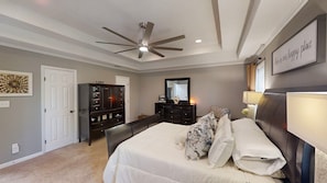 A bedroom with a bed, a dresser, a ceiling fan, and a wall-mounted mirror.