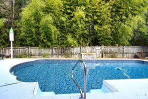 A swimming pool with a metal ladder, surrounded by a wooden fence and lush greenery. - 5  Miles to Course - Come Back, Relax in our Salt Water Pool & Outdoor Kitchen! (MARTINEZ)