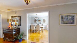 Uma sala de jantar com uma mesa e cadeiras de madeira, um lustre e um quadro na parede.