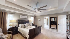 Quarto com uma cama grande, um ventilador de teto e vista para o corredor.