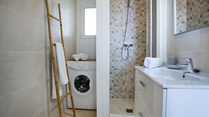 Une salle de bain moderne équipée d’un lave-linge, d’une douche et d’un lavabo.