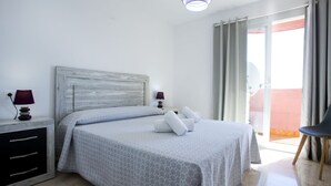 Une chambre d’hôtel avec un lit, deux tables de chevet, une chaise et une vue sur l’extérieur.