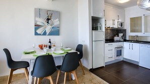 Une cuisine moderne avec des meubles blancs, un four encastré et un four à micro-ondes.