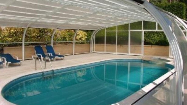 An indoor swimming pool with a covered area and lounge chairs.