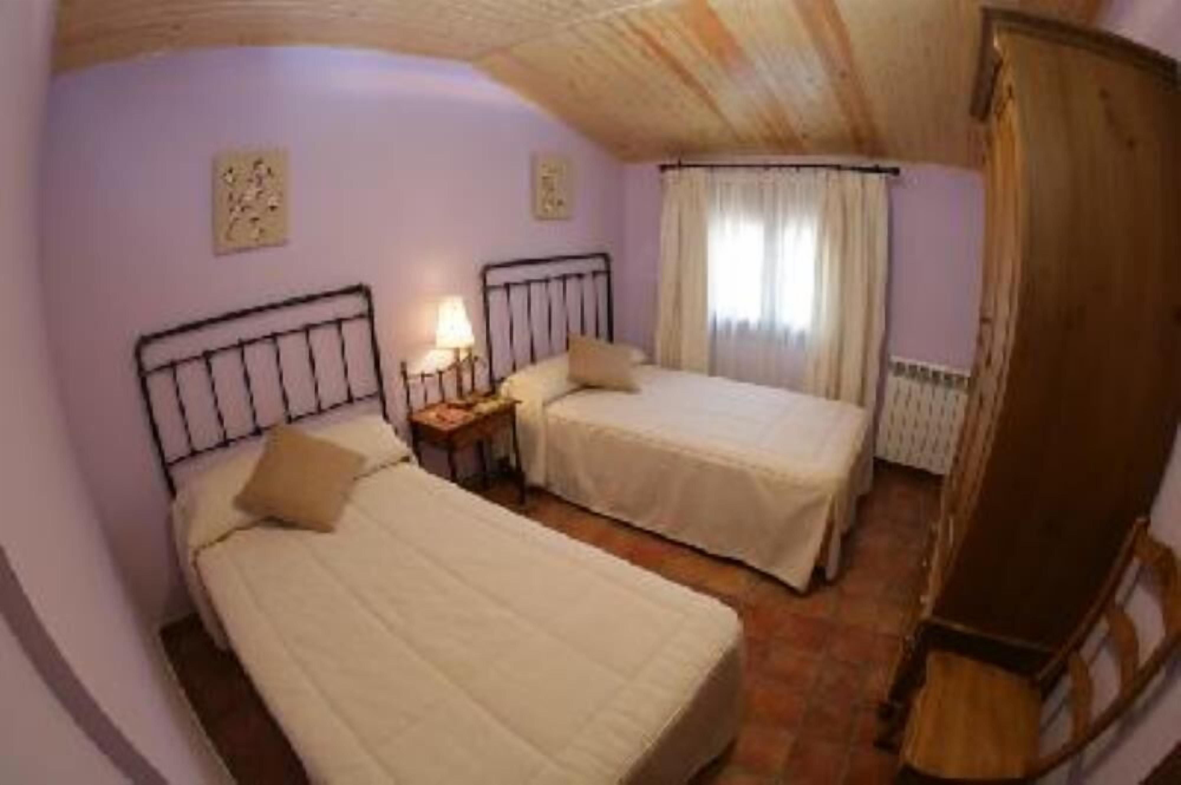 Una habitación con dos camas, un armario de madera y un radiador.