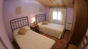 Una habitación con dos camas, un armario de madera y un radiador.
