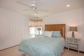 Relax in this serene bedroom with a large bed, two nightstands, and a ceiling fan.