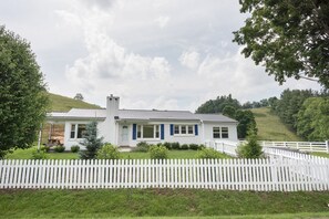 Set amidst lush green hills, this charming house offers a serene retreat with a cozy front porch and a picturesque view.