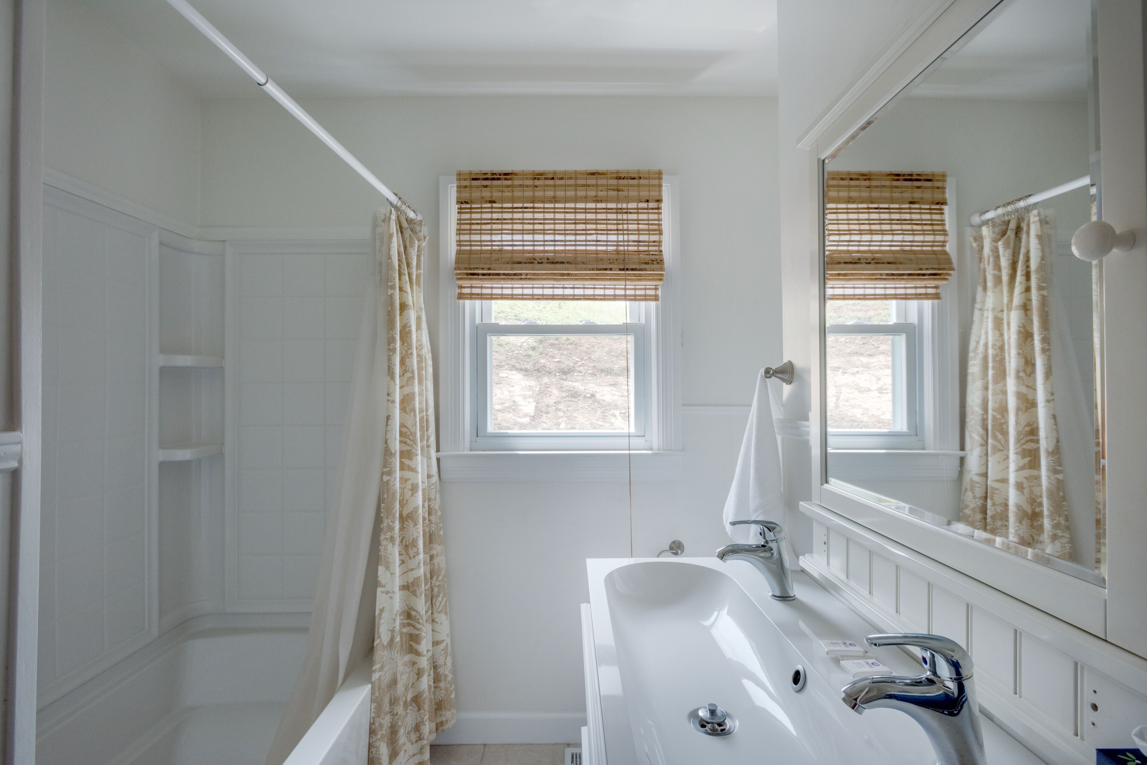 Une salle de bain avec une baignoire, un lavabo et une fenêtre donnant sur un beau paysage.